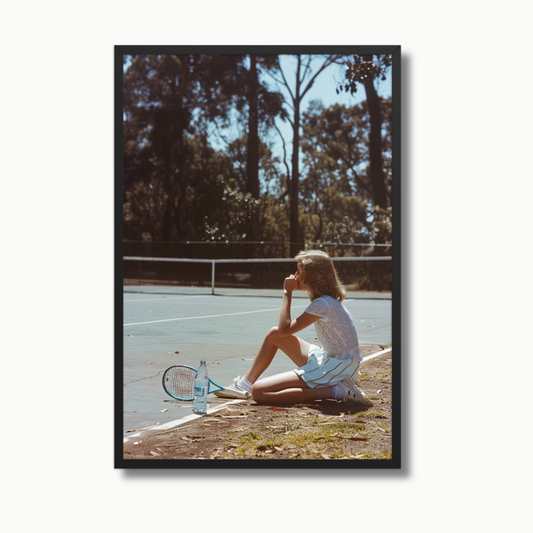 A young tennis player sits courtside under the sun, pausing in serene reflection after a match on a vintage tennis court surrounded by nature. This elegant luxury tennis wall art captures a moment of calm and focus, perfect for upscale interiors, sports-themed decor, or collector-worthy fine art prints. Printed on ultra-premium luster photo paper, this high-end tennis artwork adds sophistication to any modern home or gallery wall.